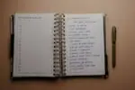 Otwarty notes z listą noworocznych postanowień i leżący obok długopis.