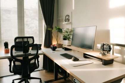 Nowoczesne stanowisko pracy z ergonomicznym fotelem, monitorem na podstawce i roślinami.