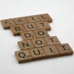 Drewniane płytki z literami ułożone w napis: Fail but do not quit.