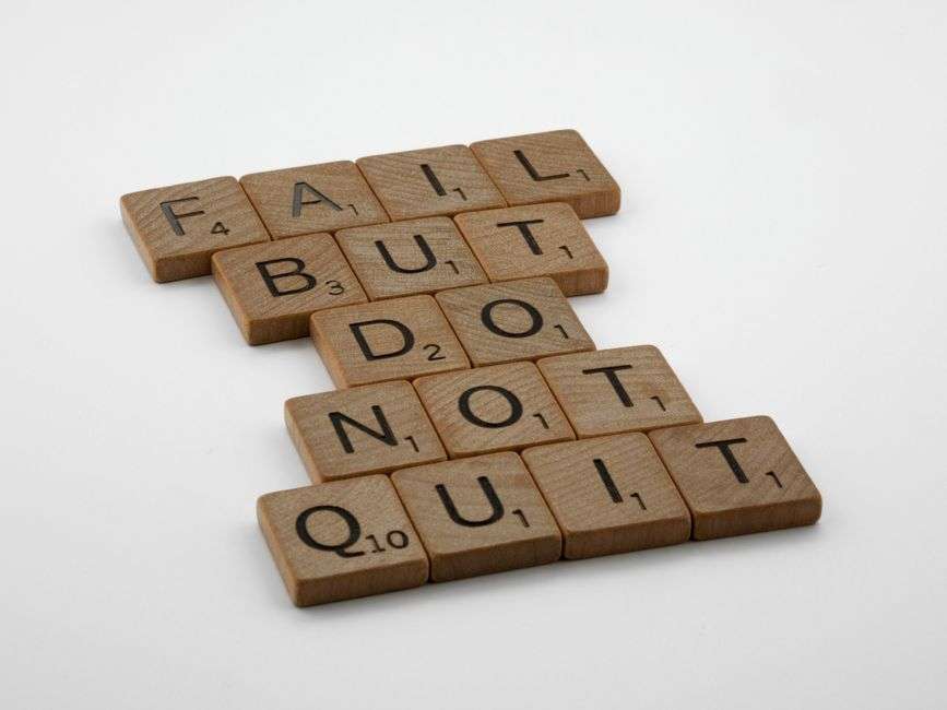 Drewniane płytki z literami ułożone w napis: Fail but do not quit.