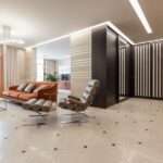 Nowoczesny salon z pomarańczową kanapą, jasną podłogą i przeszklonymi szafami.