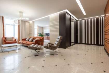 Nowoczesny salon z pomarańczową kanapą, jasną podłogą i przeszklonymi szafami.