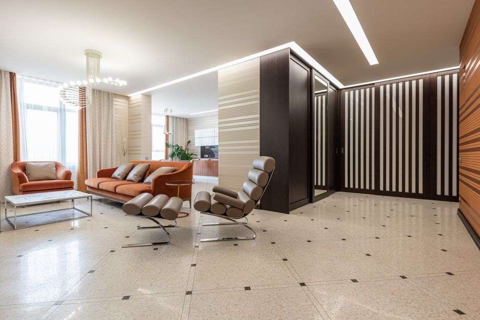Nowoczesny salon z pomarańczową kanapą, jasną podłogą i przeszklonymi szafami.