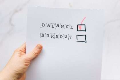 Ręka trzyma kartkę z wyrazami BALANCE i BURNOUT oraz zaznaczonym wyborem BALANCE.