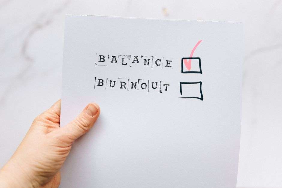 Ręka trzyma kartkę z wyrazami BALANCE i BURNOUT oraz zaznaczonym wyborem BALANCE.