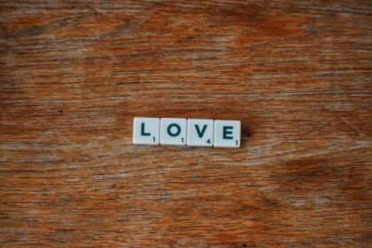 Drewniane płytki do gry w scrabble tworzące napis LOVE na drewnianym stole.