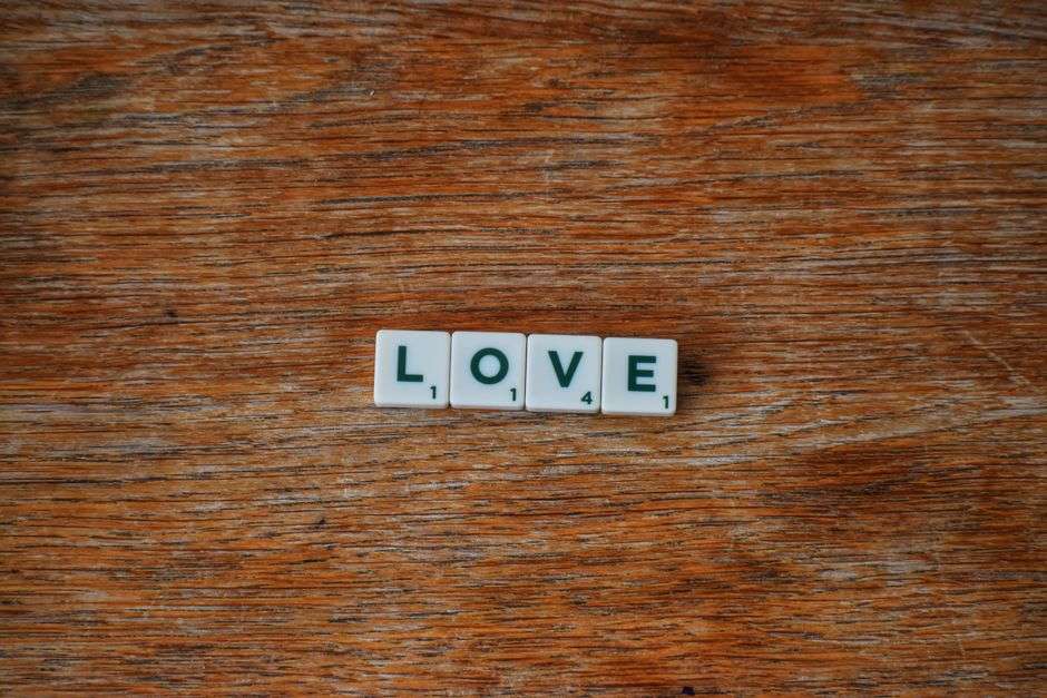 Drewniane płytki do gry w scrabble tworzące napis LOVE na drewnianym stole.