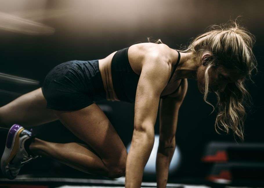 Kobieta wykonująca ćwiczenie typu mountain climber w stroju sportowym.