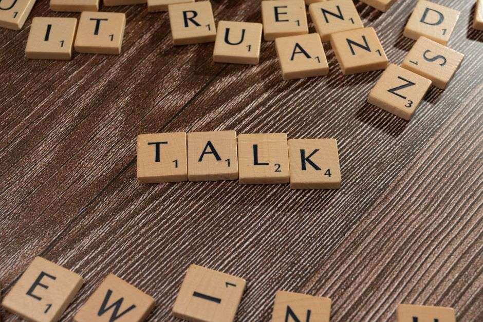 Drewniane płytki z literami ułożone w słowo TALK na ciemnym drewnianym tle.